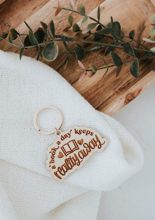 A Book A Day Keeps Reality Away Wooden Keychain image 0